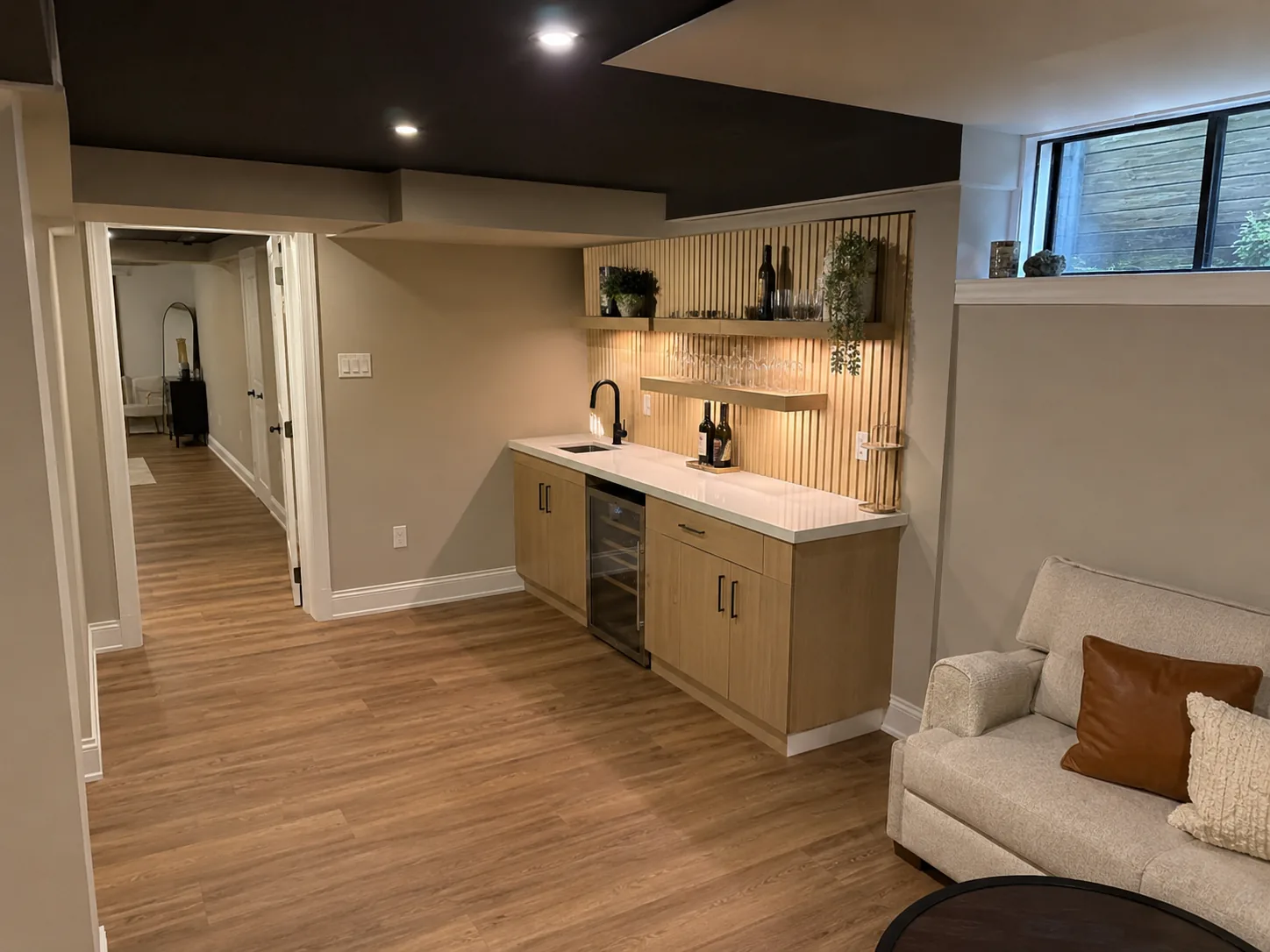Finished basement with oak wet bar, floating shelves, and lounge seating