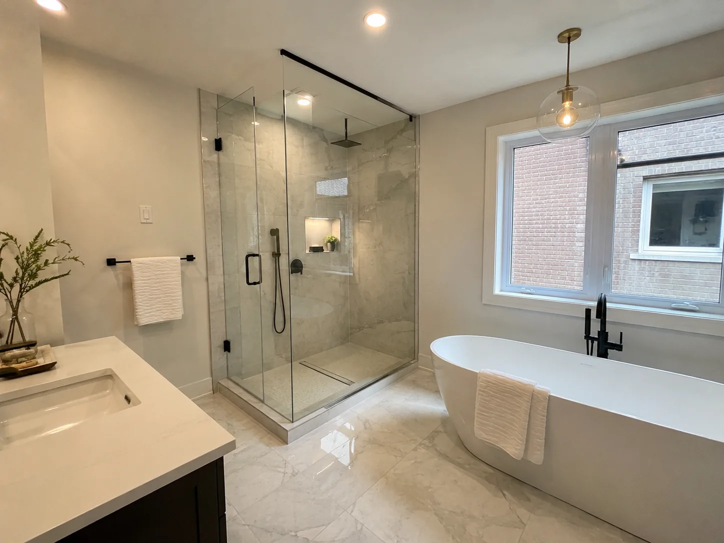 The same bathroom after renovation: glass walk-in shower and freestanding tub