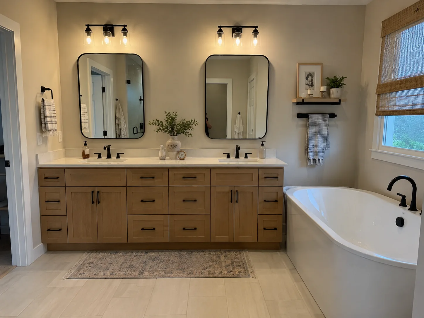 Renovated bathroom with oak double vanity, black fixtures, and freestanding tub