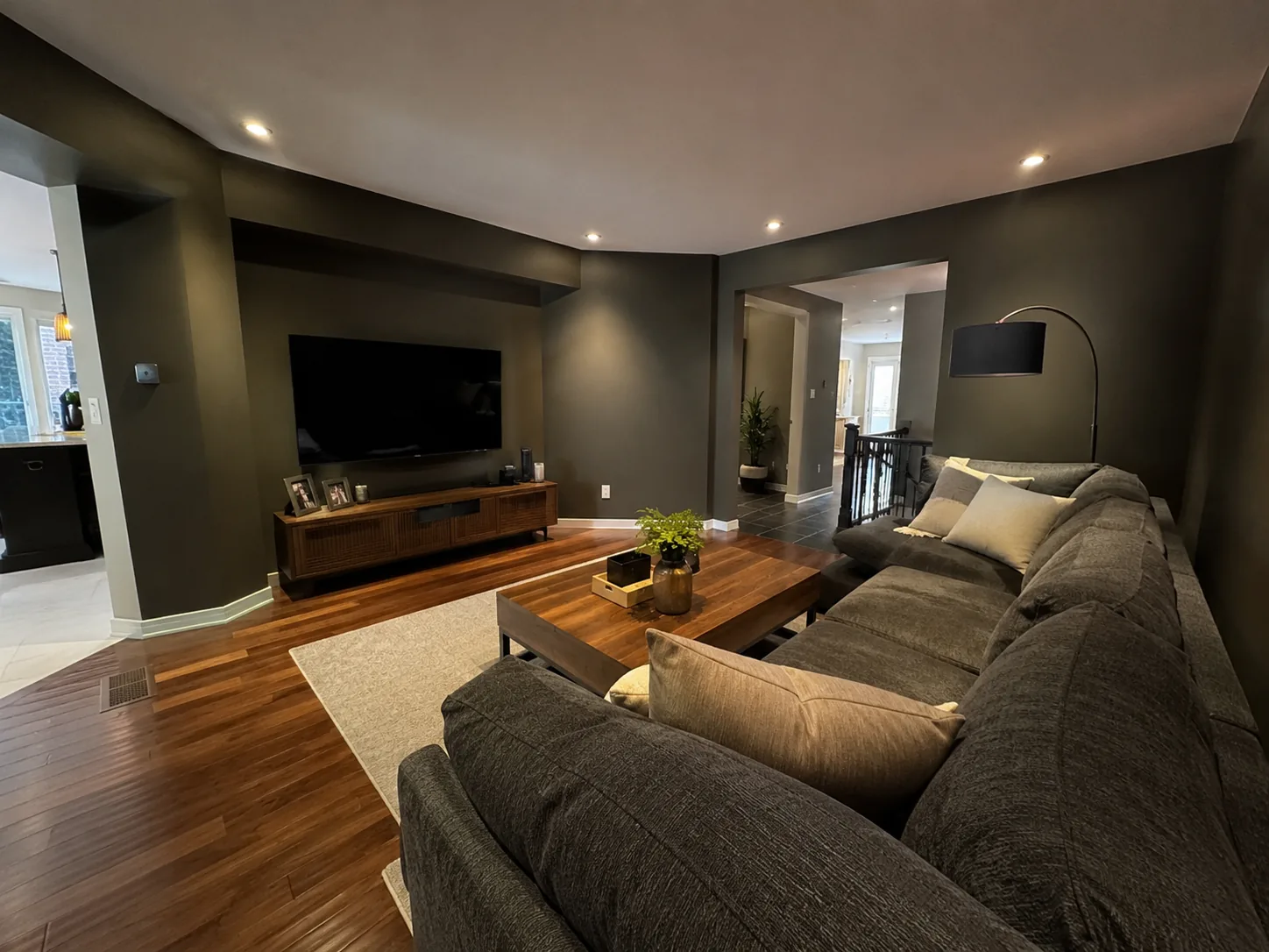 Moody dark green living room with sectional and mounted TV